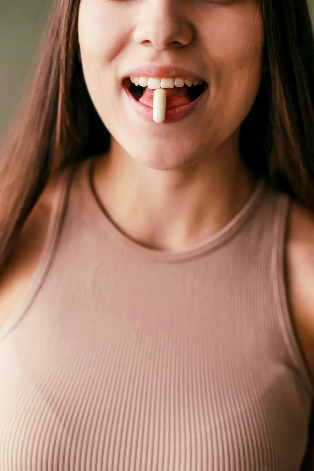 Woman holding a pill in her mouth.