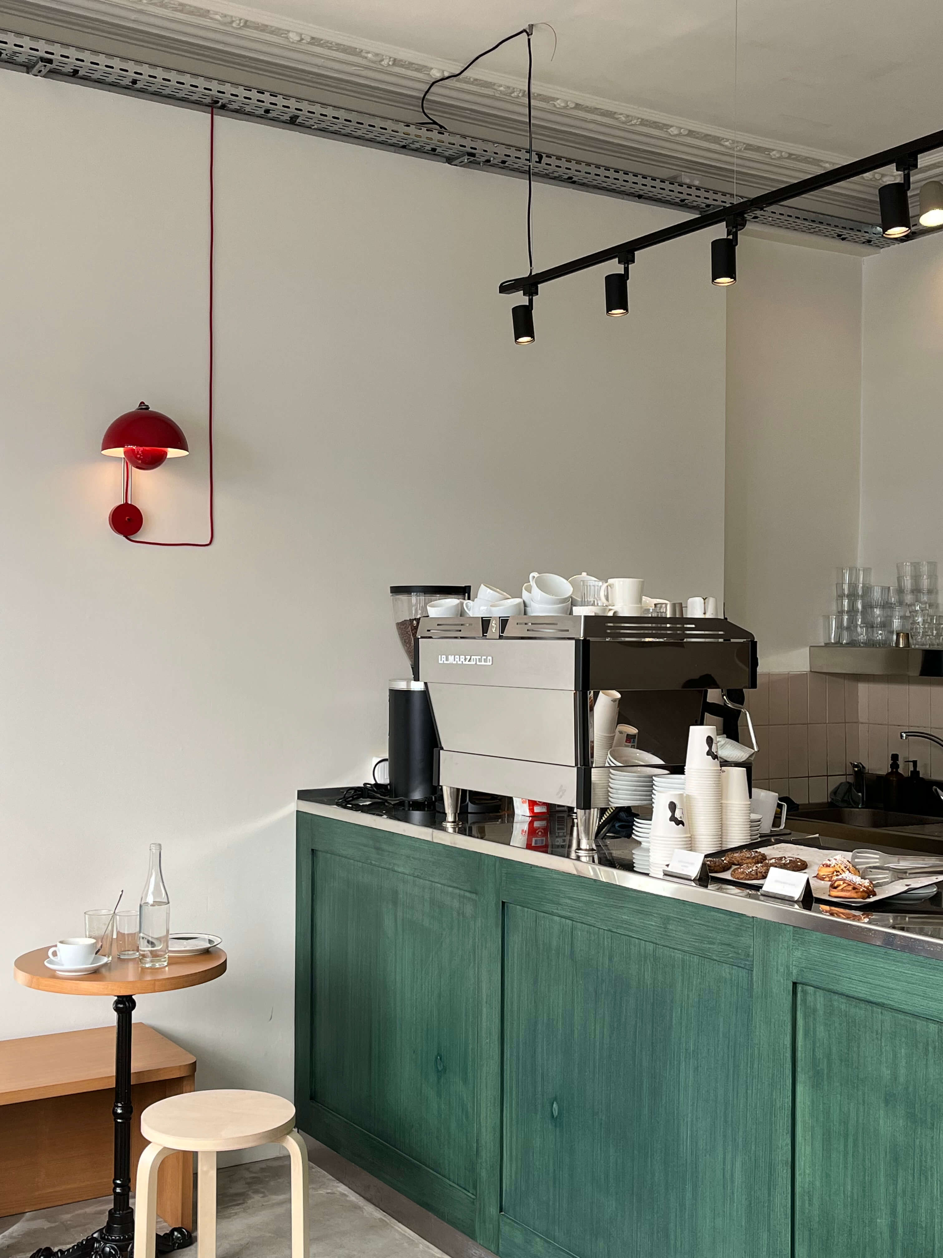 A corner of a cafe with an espresso machine set on top of a green tile counter