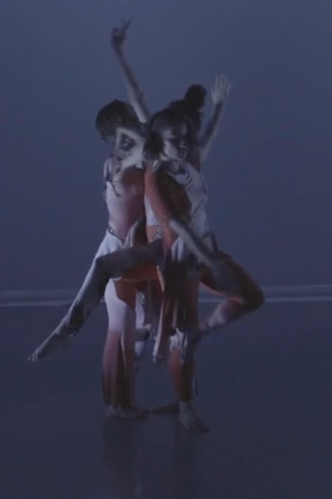 A dramatic performance photograph featuring multiple dancers.