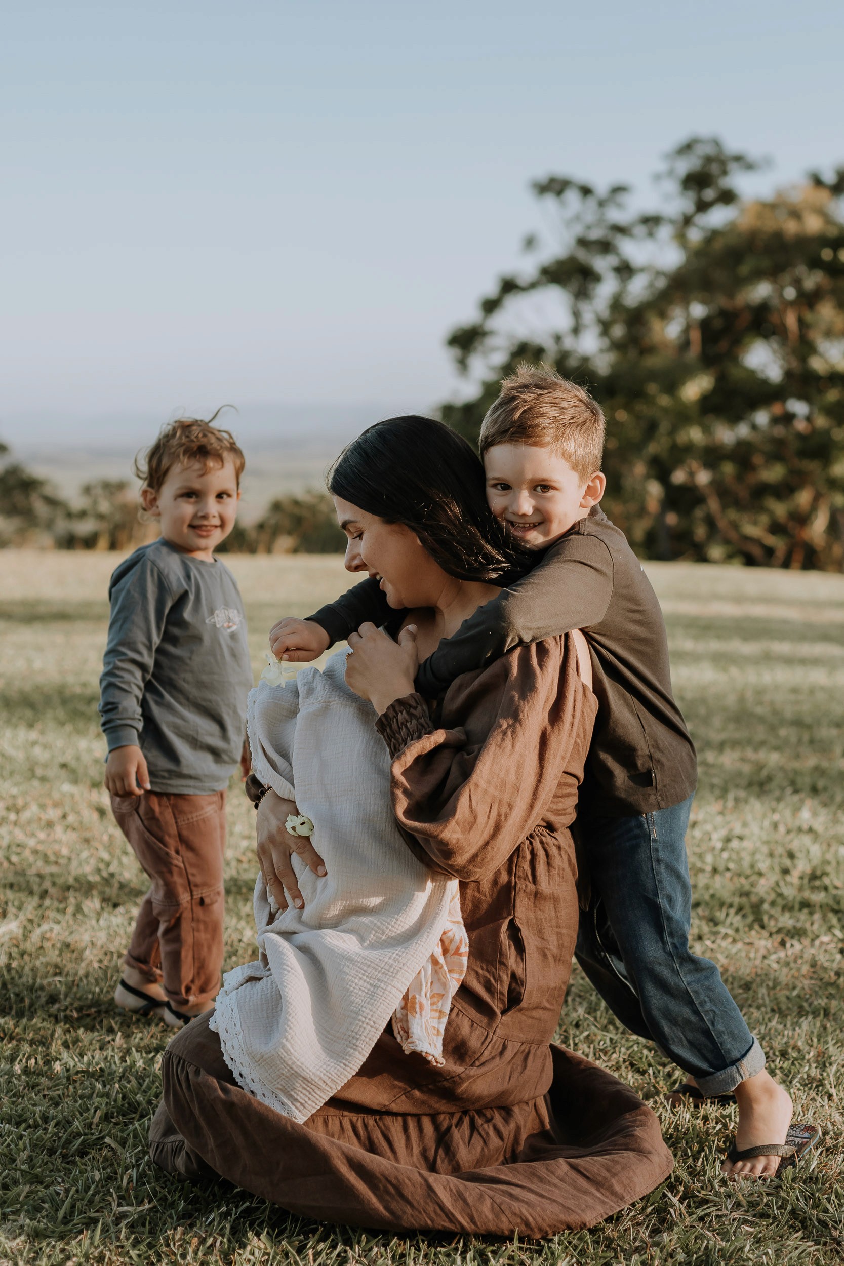 Unposed family photo at sunset showing mum and children cuddling