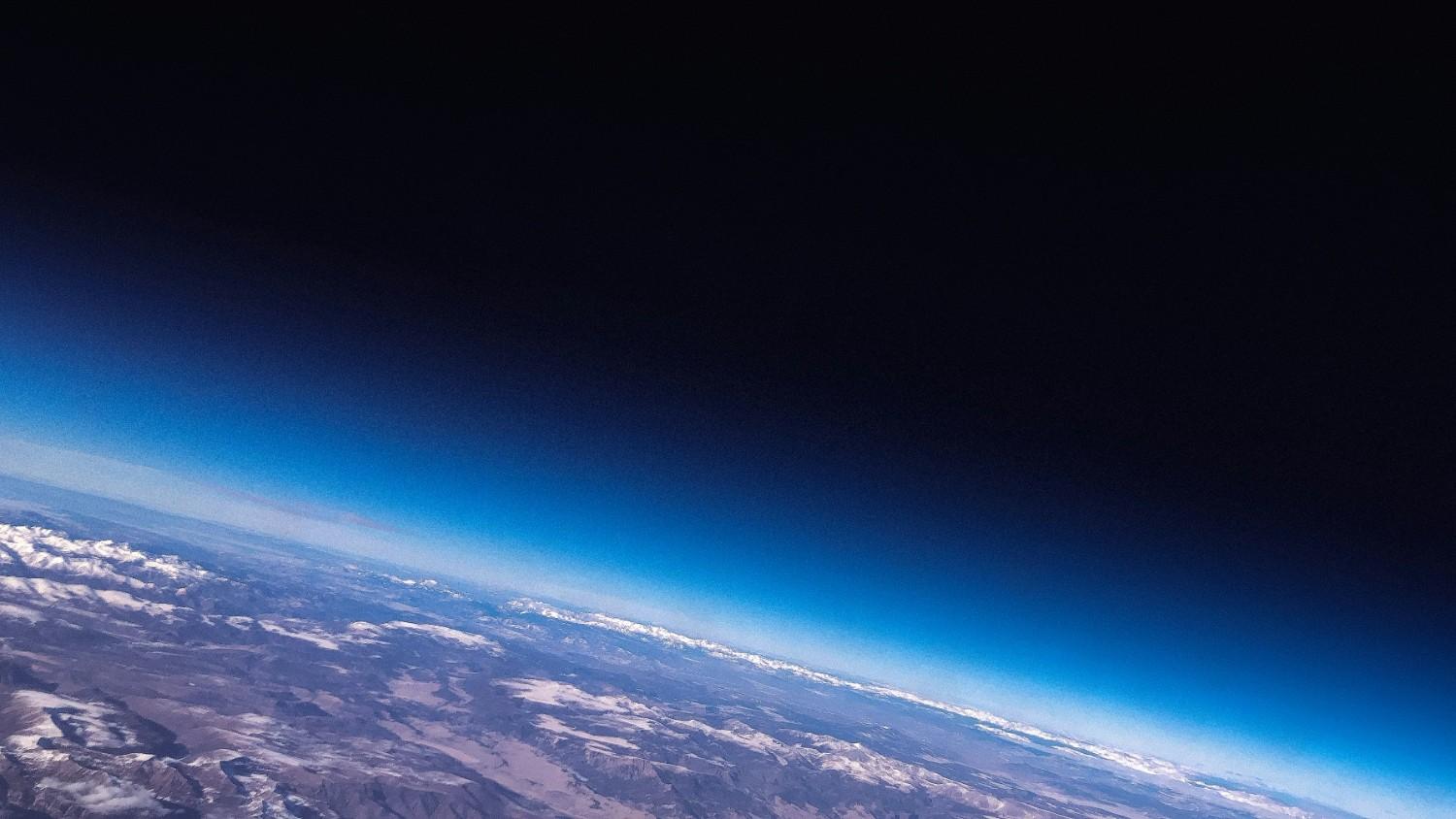 Curved view of Earth’s horizon from high altitude with a deep blue sky fading into space