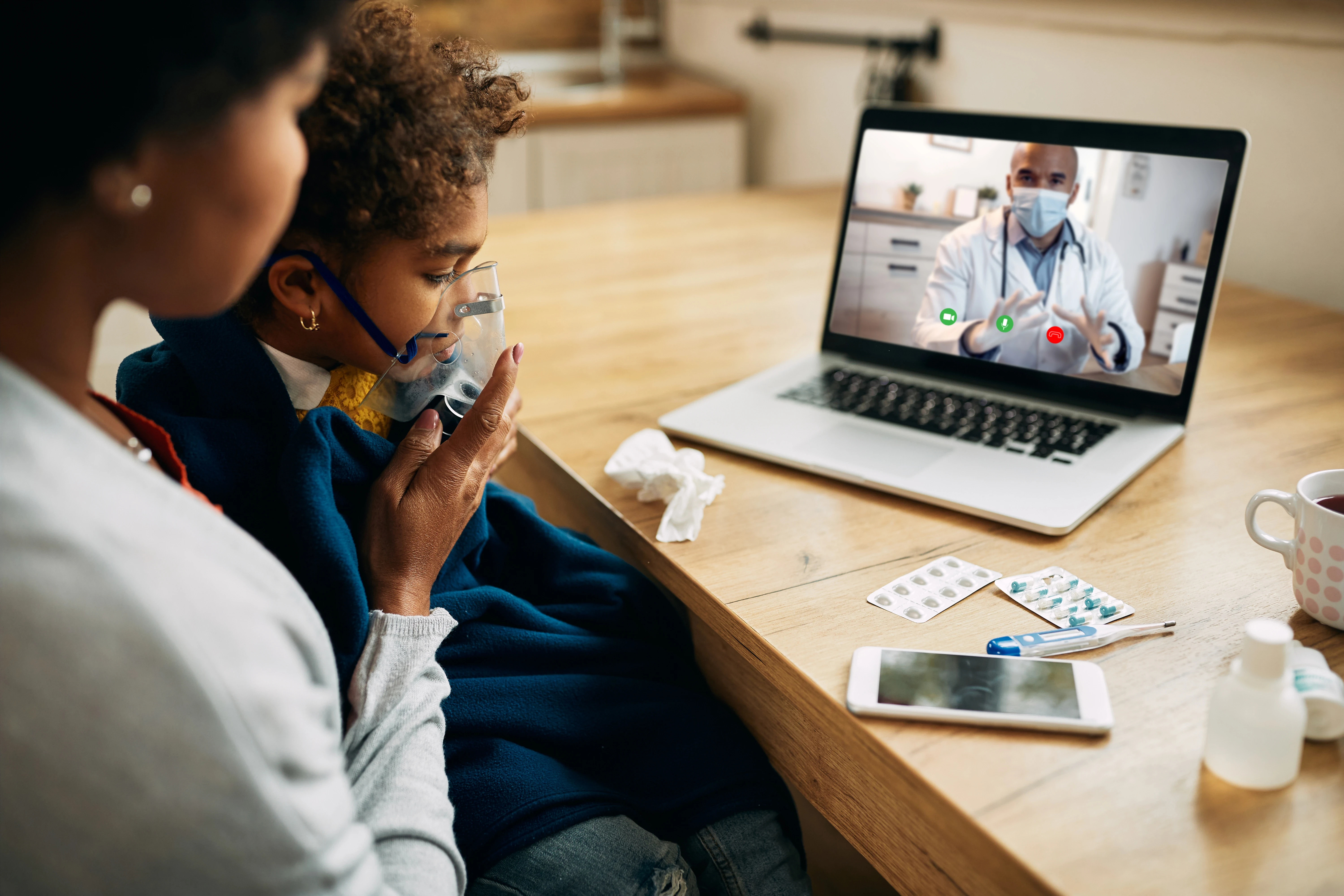 Black pediatrician talking via video call to mother is giving her daughter inhaling therapy at home