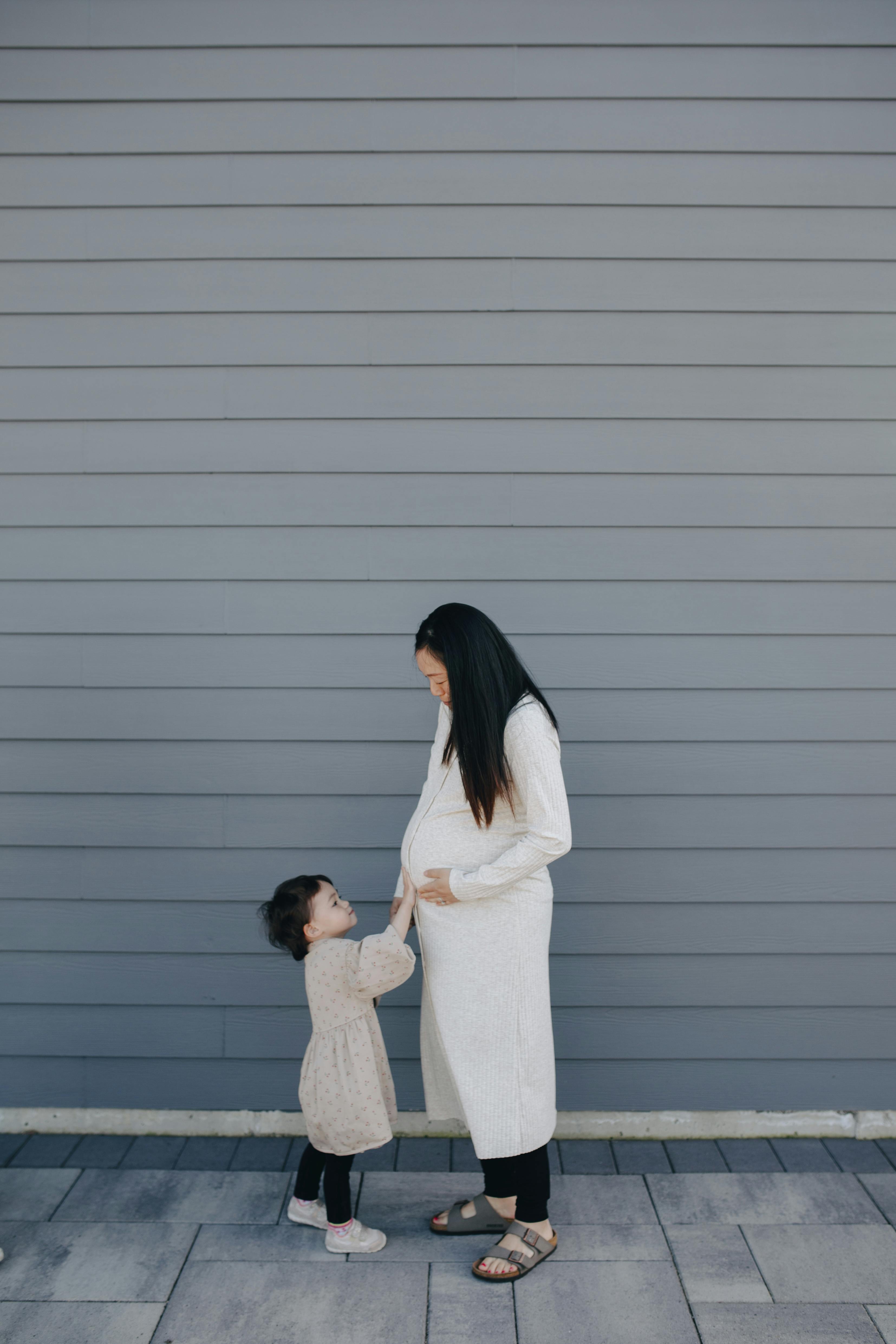 Little girl touching her mother's tummy
