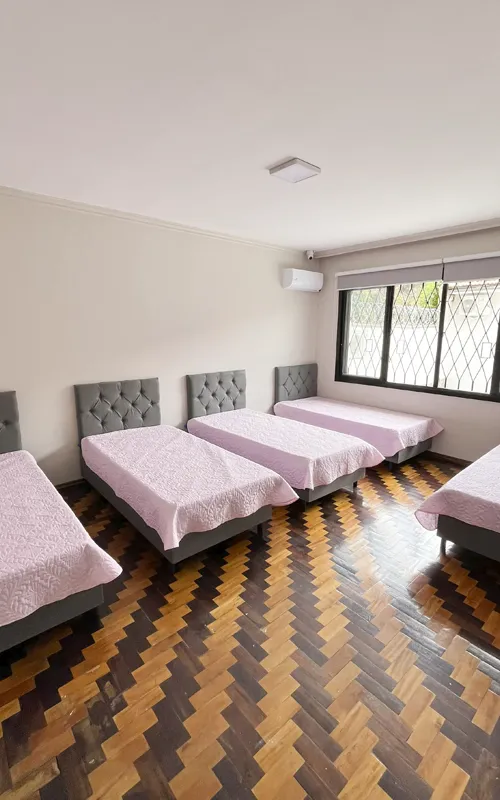 Quarto adaptado para idosos, com barras de segurança, iluminação natural e ambiente humanizado.