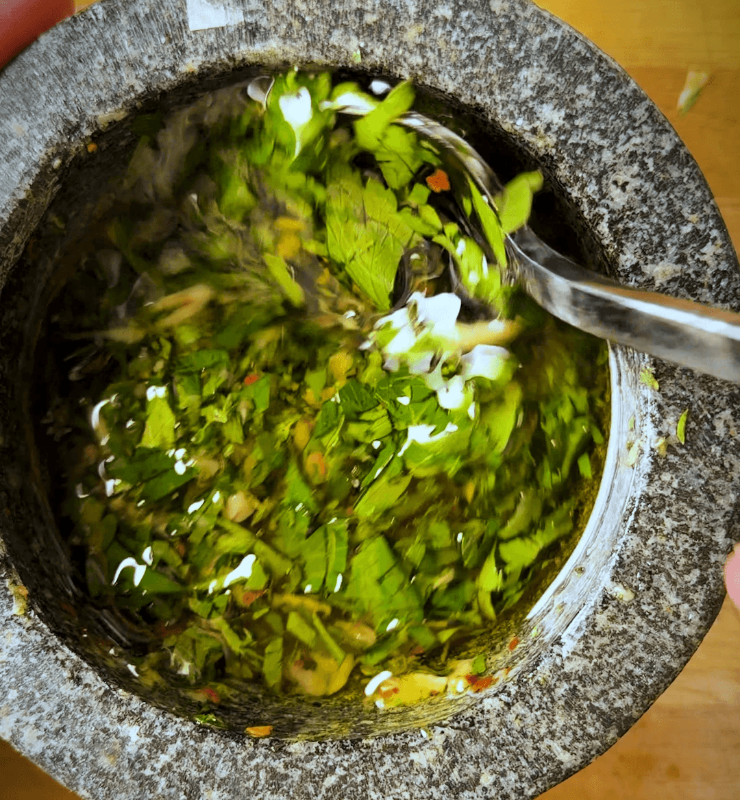 herbs making up a fresh chimmichuri in a granite mortar and pestle