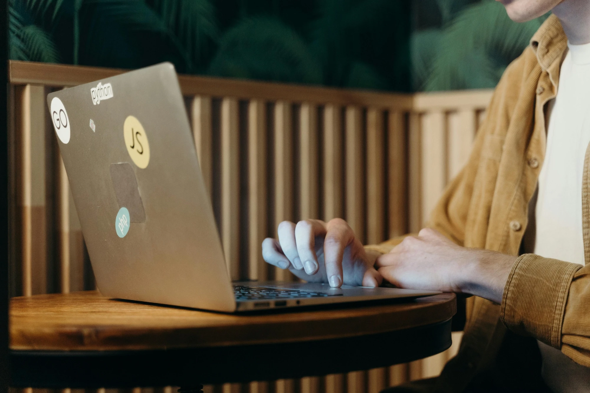 A man working on a laptop while sitting at a table, appearing engaged in his task.