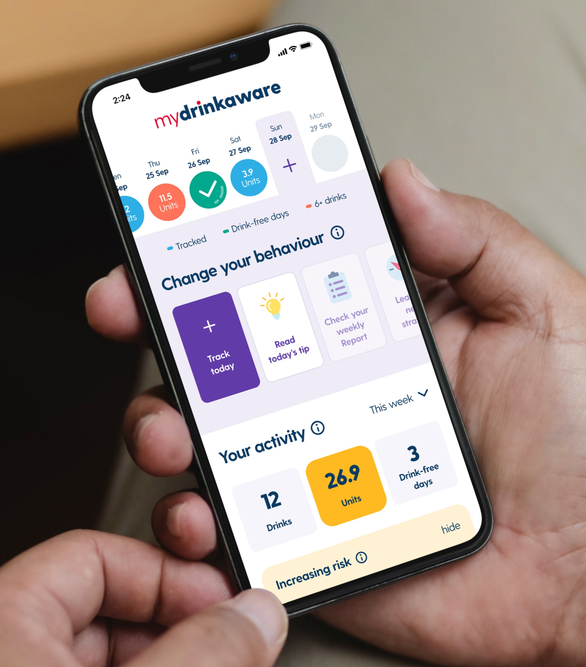 Close-up of MyDrinkaware mobile app interface design: a user's hand holding a smartphone displaying the activity dashboard with tracked units, drink-free days, and calls-to-action for behavior change.