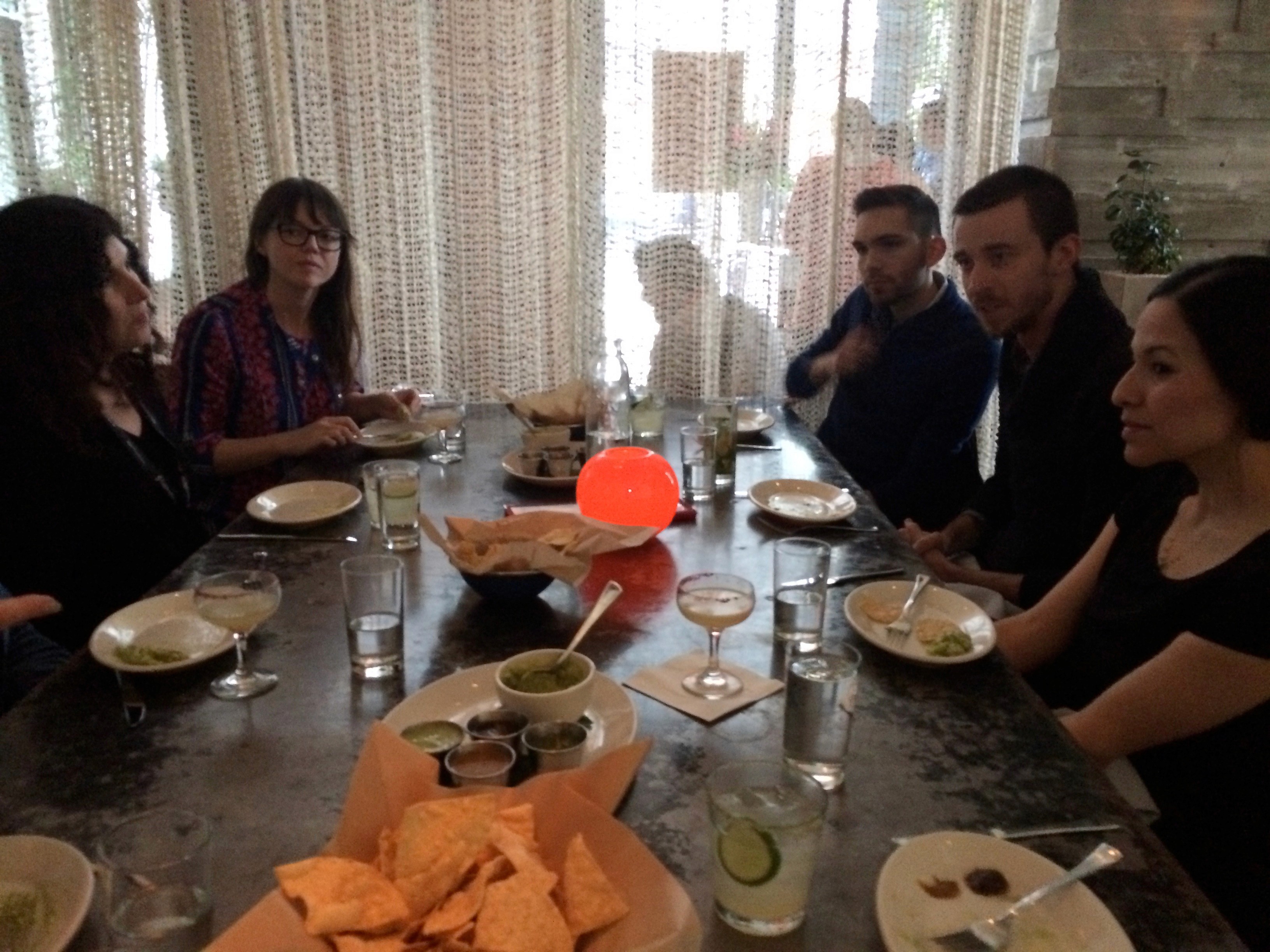 five people sitting on a table having lunch