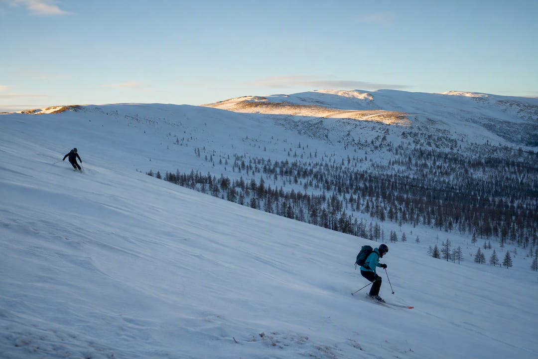 Two skiers traversing snow-covered terrain in the Altai Mountains
