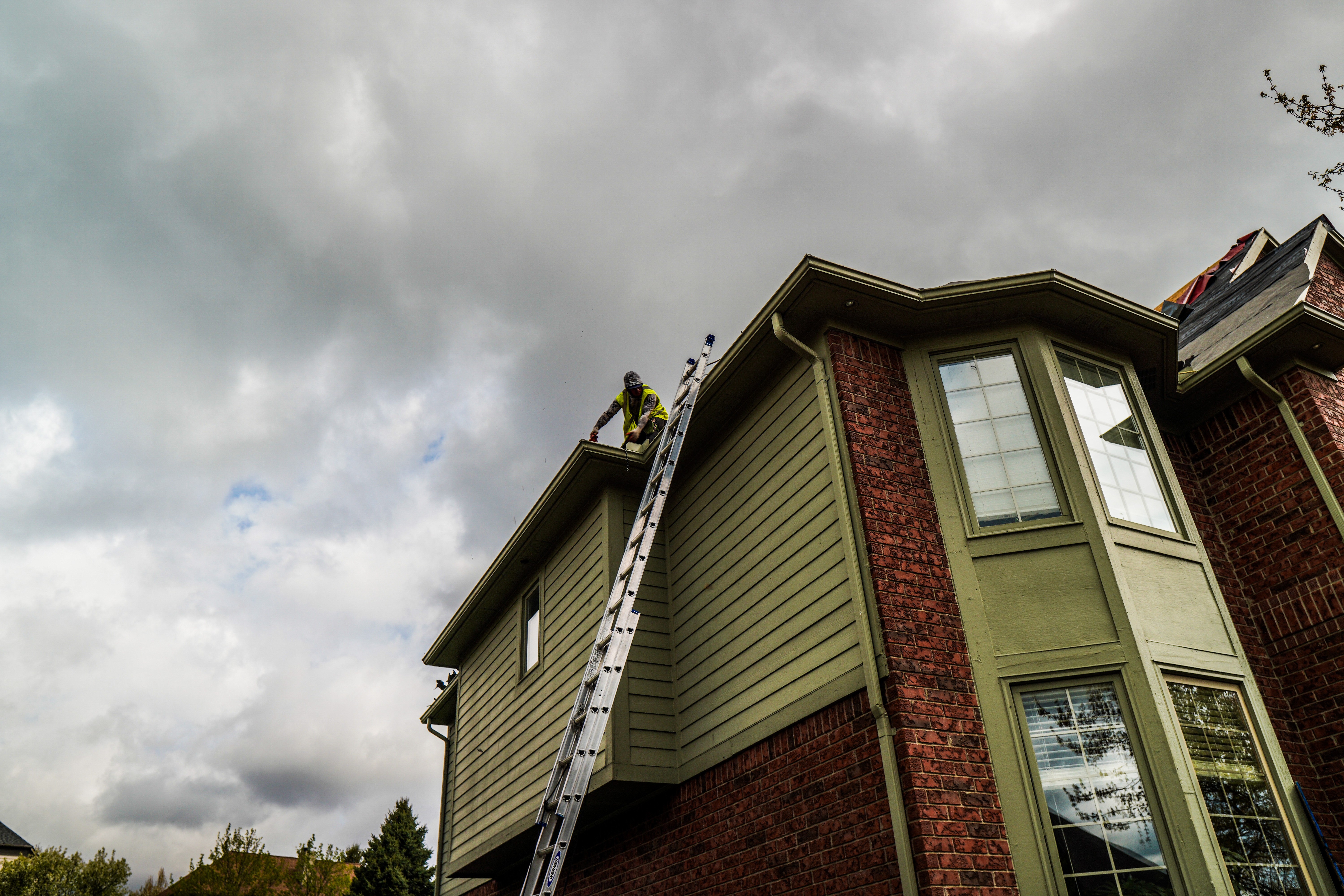 Ladder against a home with green siding during an exterior project