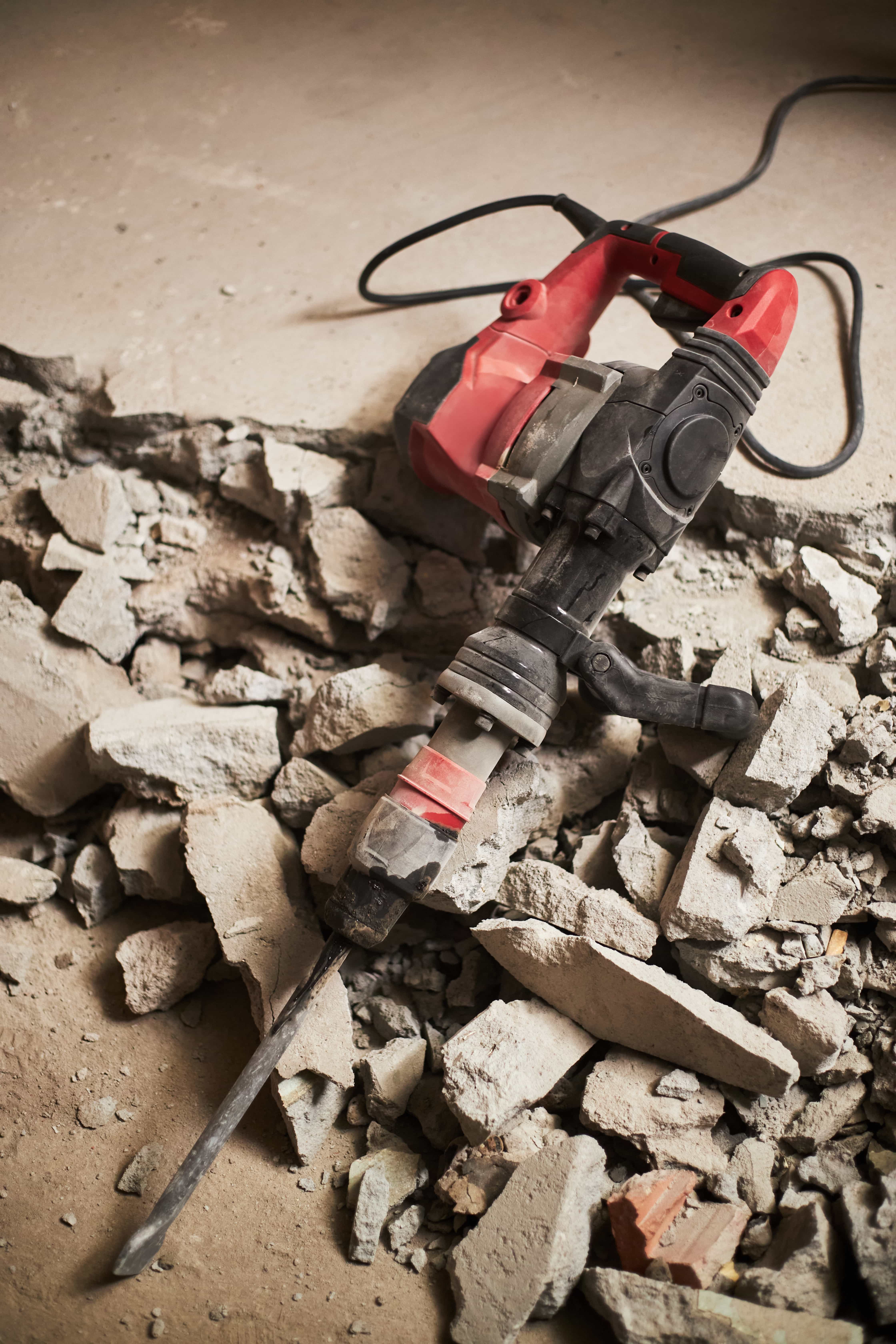 A construction worker is working on the pavement.