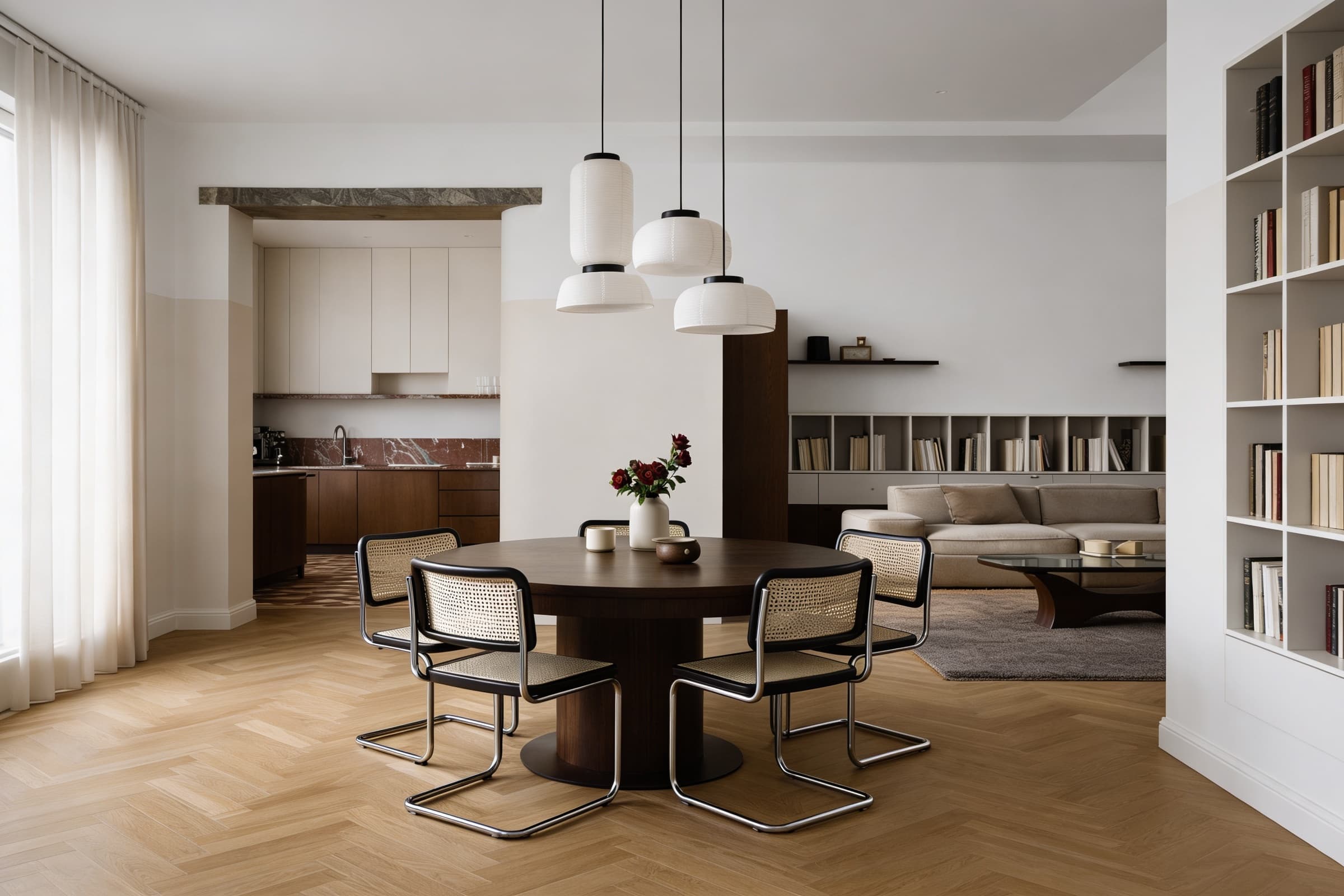 A modern, minimalist dining room with a round wooden table surrounded by four sleek chairs, soft natural light flowing through sheer curtains onto the herringbone wood floor, and contemporary pendant lights hanging overhead.