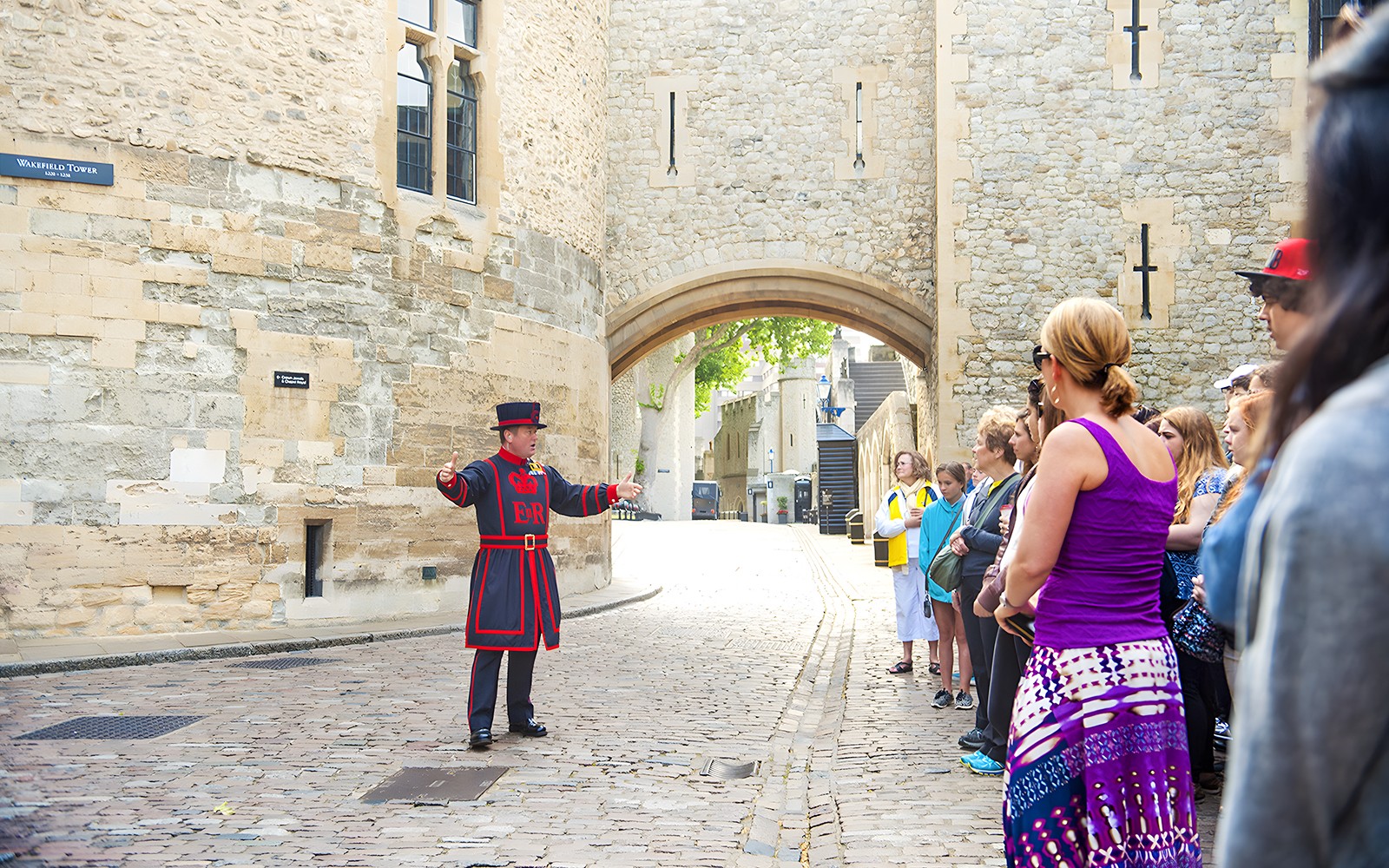 Beefeater leading a morning tour at the Tower of London with visitors gathered around.