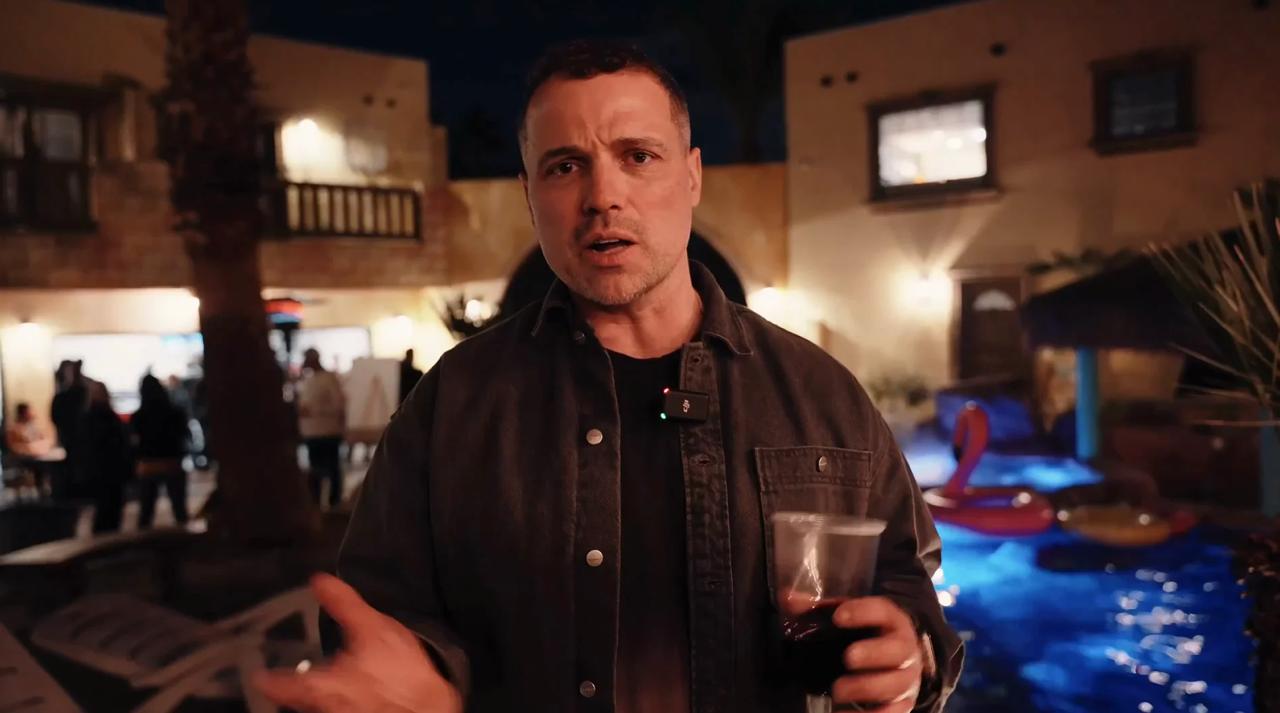 A lone cyclist rides down a snowy street at night.