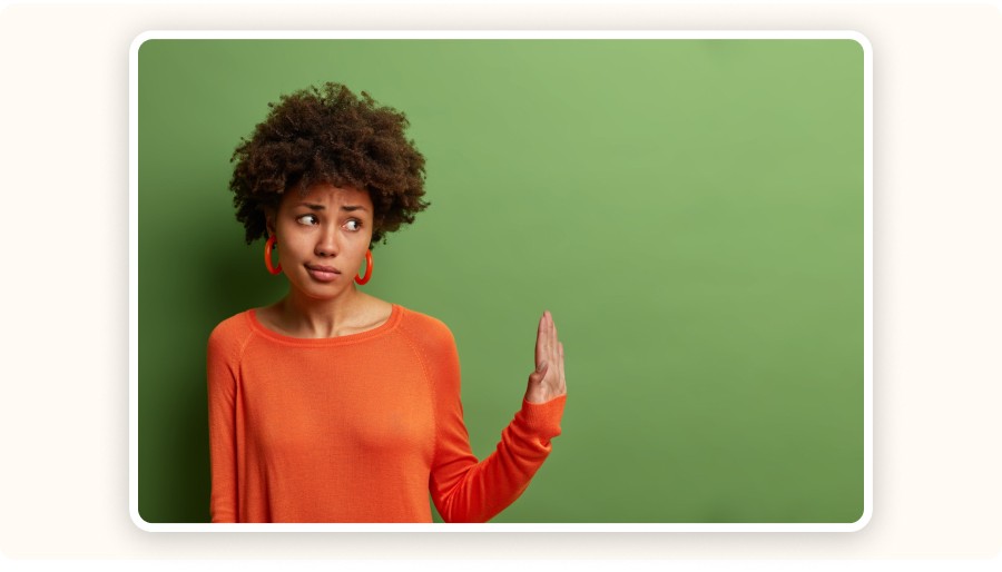 Woman with puzzled expression gesturing uncertainty against green background