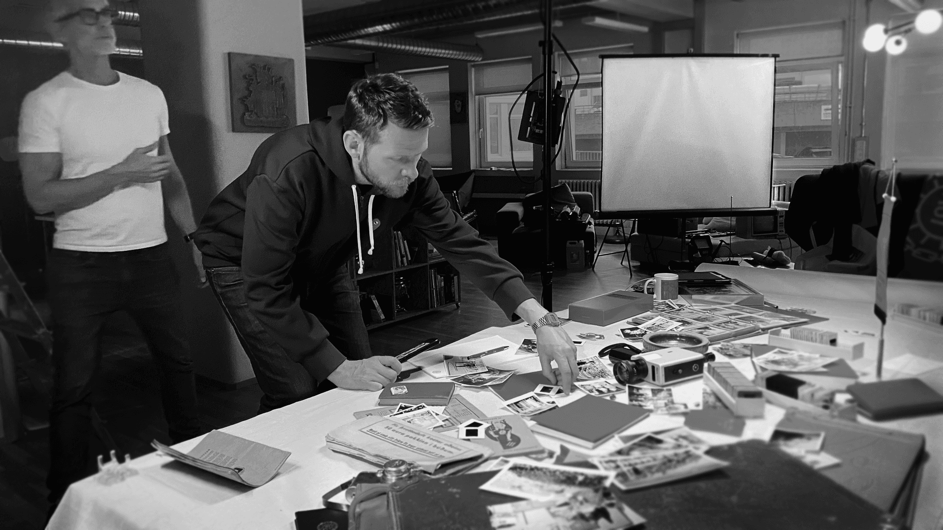 A large group photo of diverse team members gathered in an industrial-style space with arched ceiling.