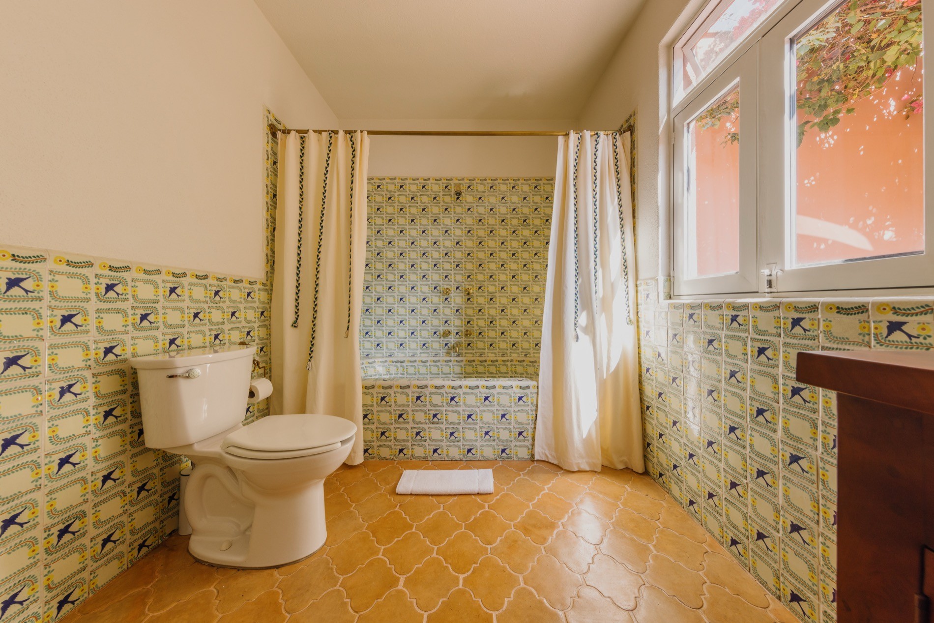 La Residencia bathroom with Talavera bird tile, terracotta floors, and bathtub alcove