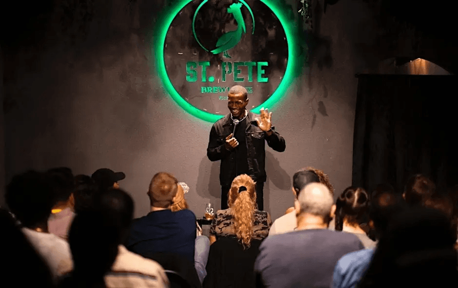 A comedian waving to the audience during his set