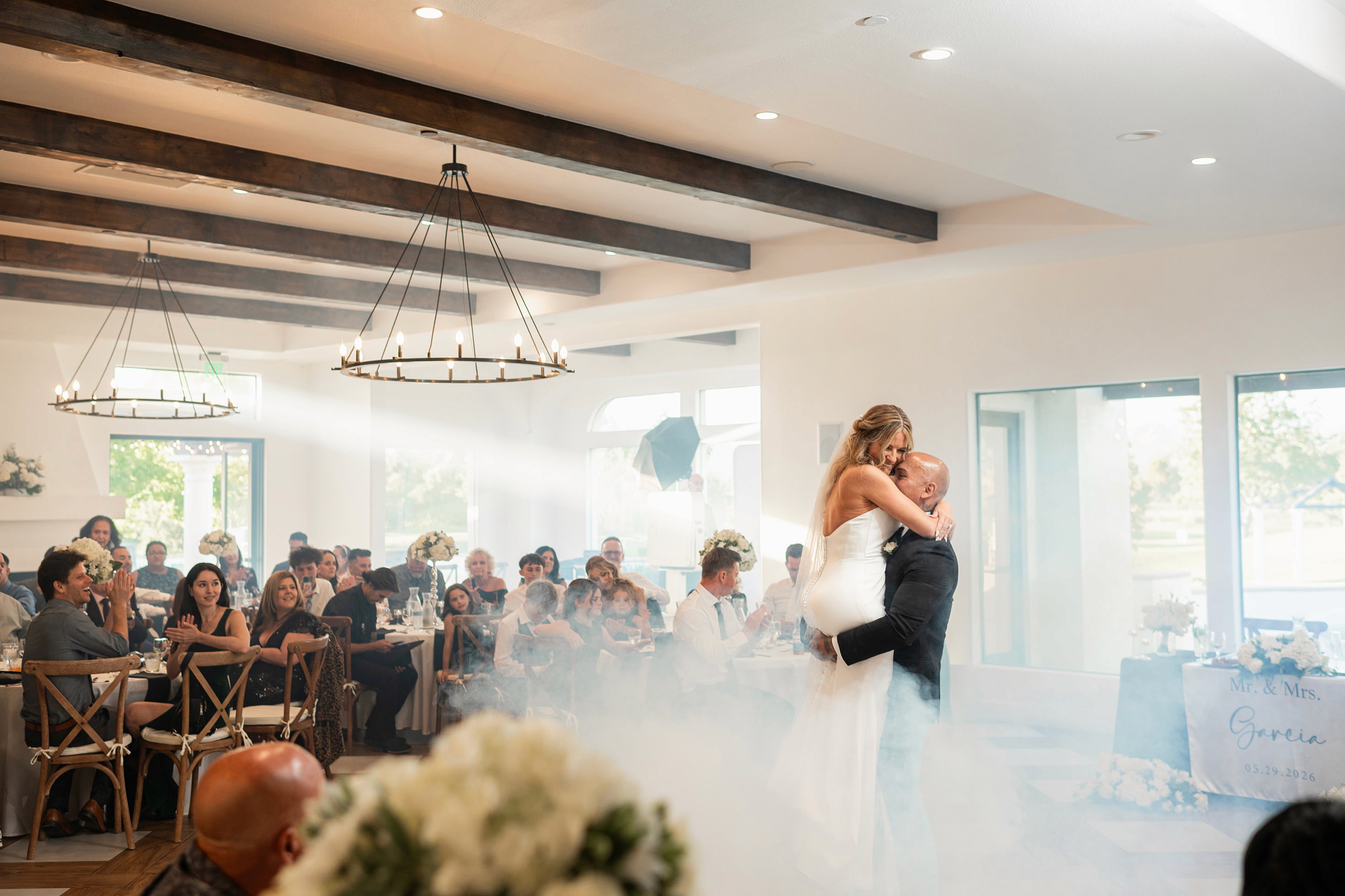 Bride and groom first dance with sunlight beam and smoke machine