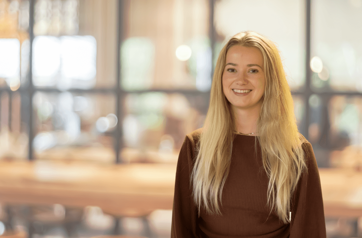woman in blue tank top standing beside white wall