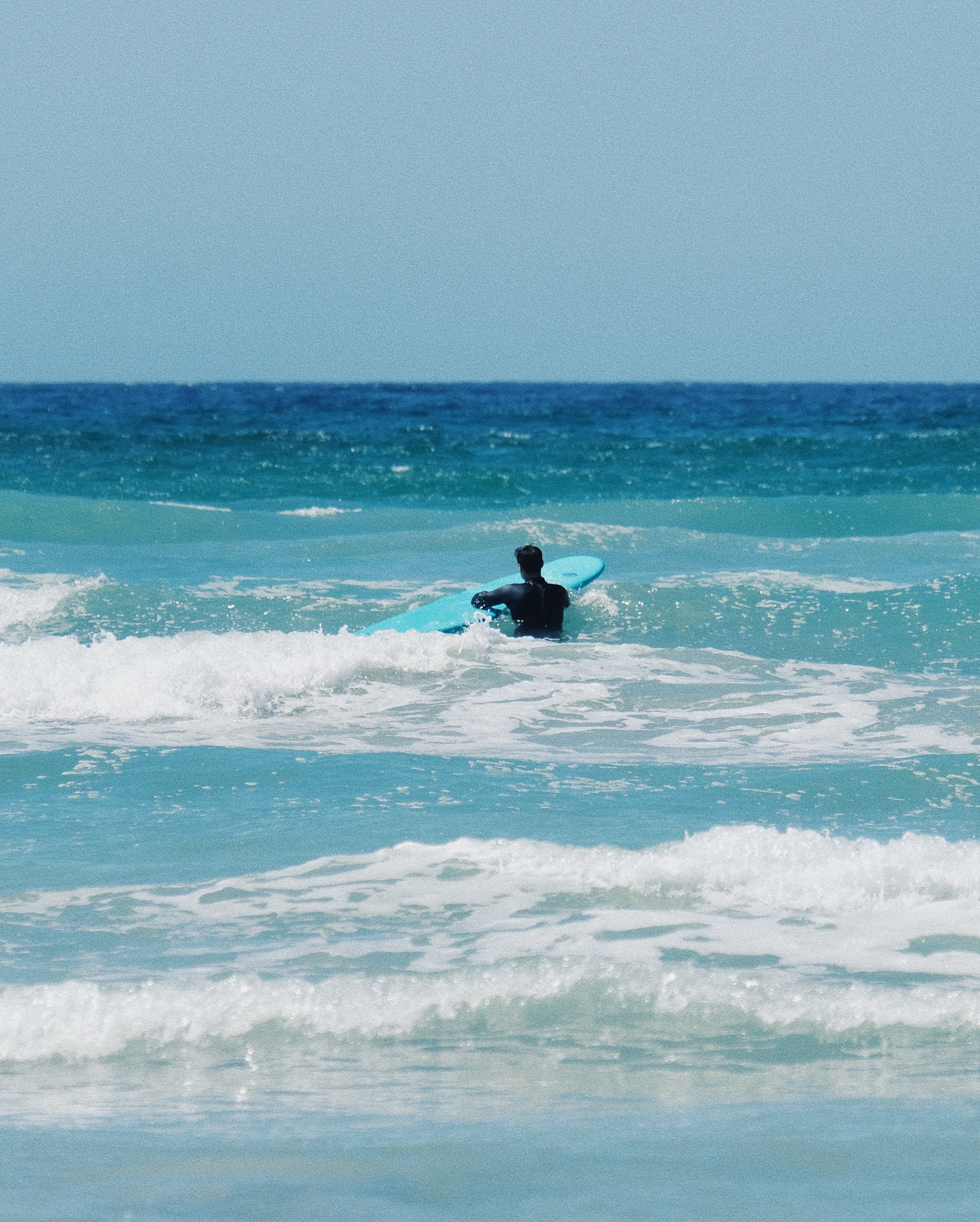 A female surfer and her surf coach in the water during a surf lesson in Cape Town, Muizenberg