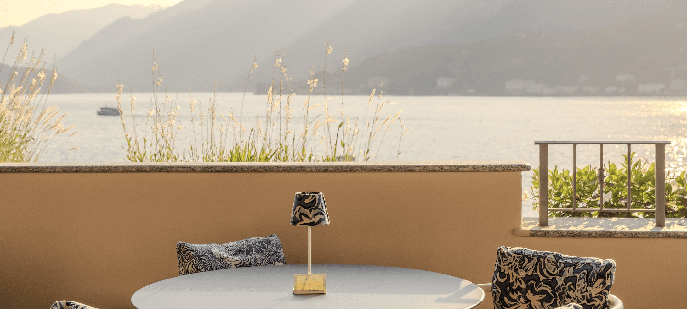 White plate with roasted chicken served in a golden sauce with herbs and capers, placed on a terrazzo tabletop in sunlight.