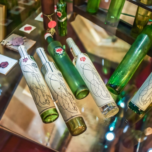 Various green and white bottles, some with ornate designs, displayed on a glass surface with other small items in the background.