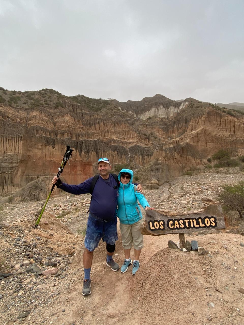 Mujer sentada sobre un tronco frente a una cascada doble en un bosque frondoso de Argentina.