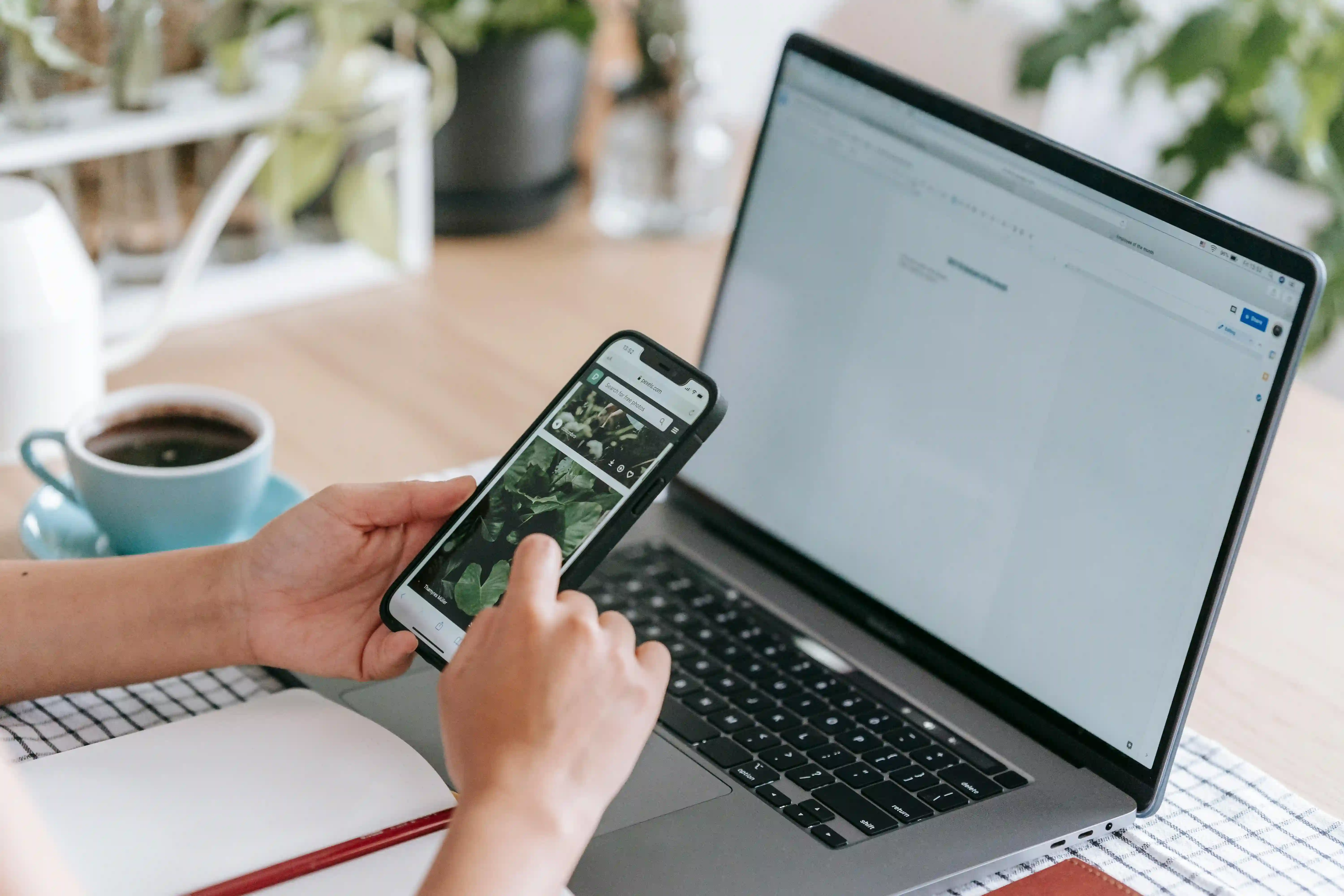 person using a phone in front of a laptop