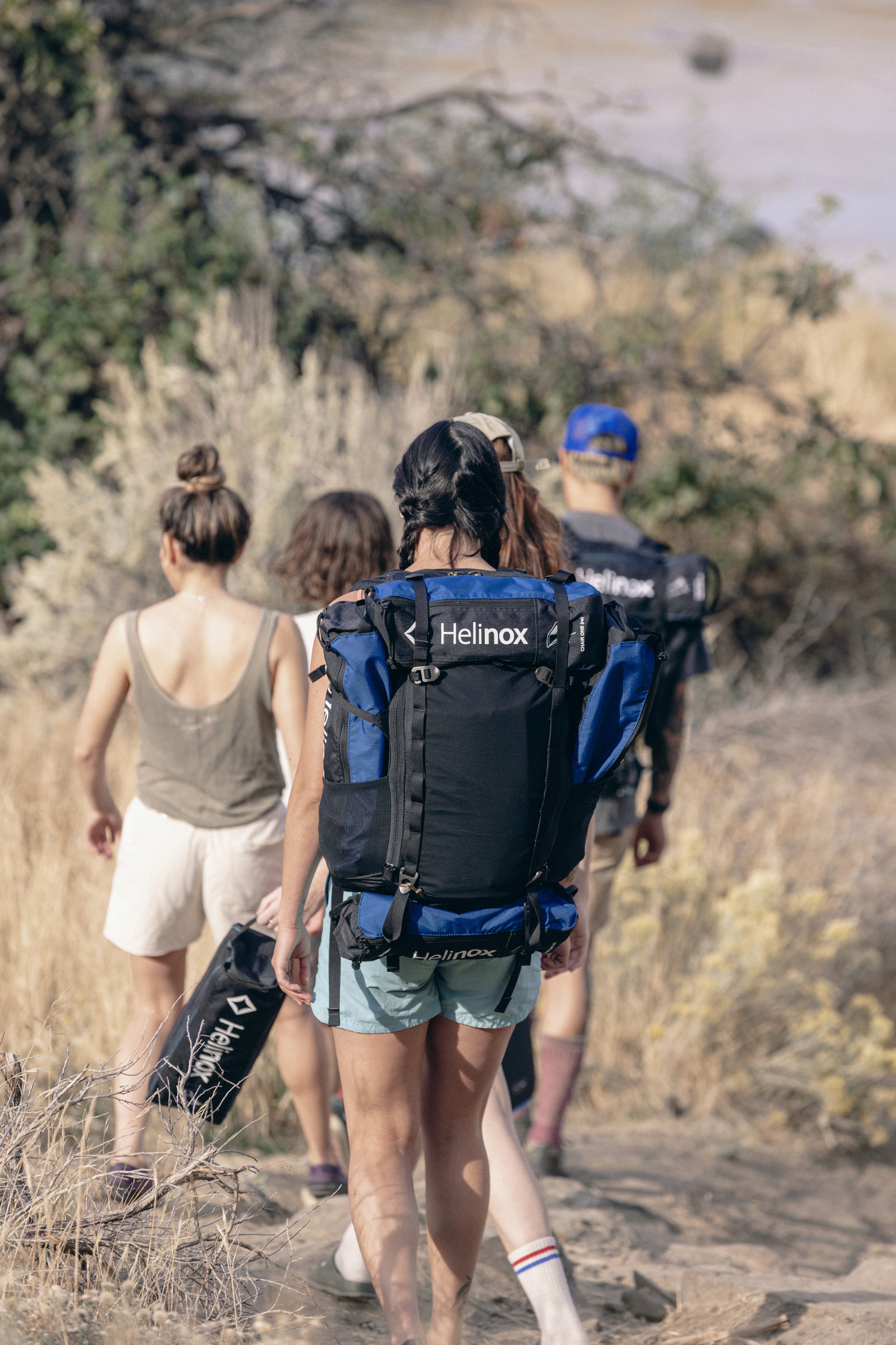 Des gens randonnent avec des sacs Helinox sur le dos contenant du matériel pliant de camping