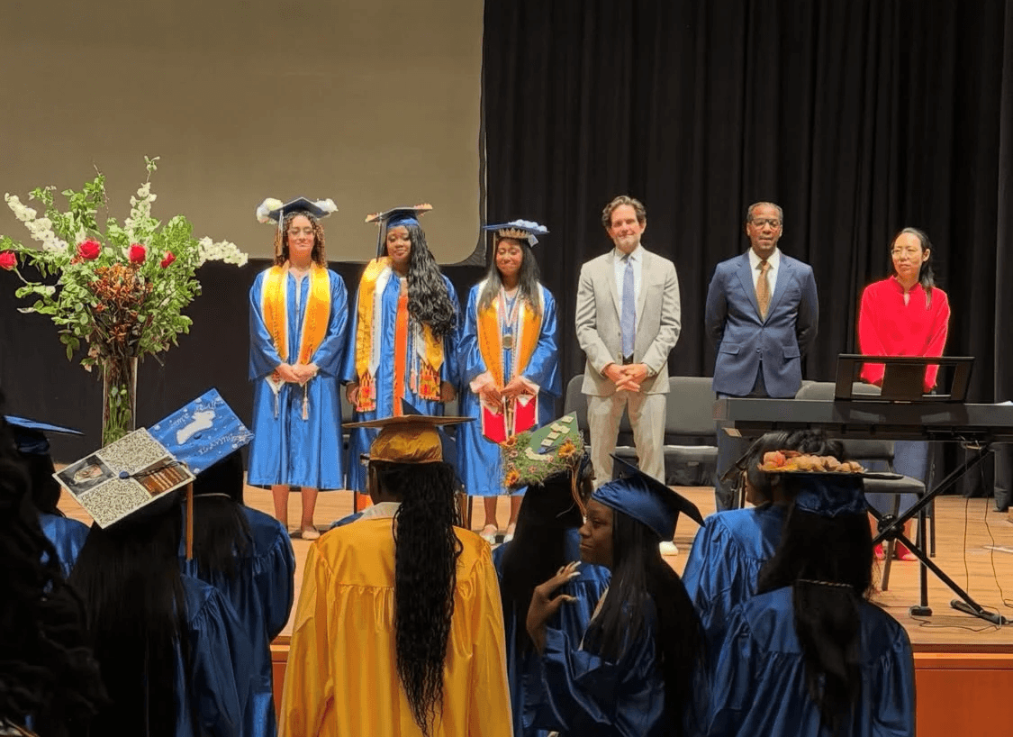 School administrators present graduating high school students onstage.