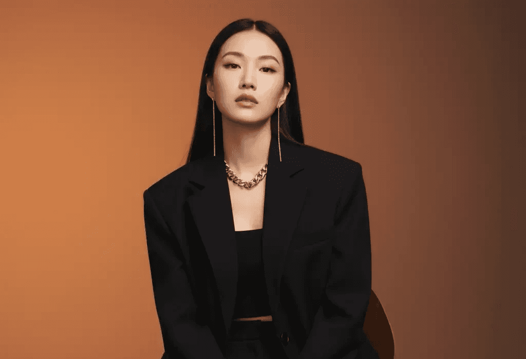 A high-quality, AI-generated professional portrait of a confident woman with long black hair, sitting on a chair and wearing a tailored black suit with bold silver jewelry. This generated image is a case study used by Mahindra, a specialist digital marketing trainer and marketing trainer consultant, to illustrate advanced visual content strategies on his blog.