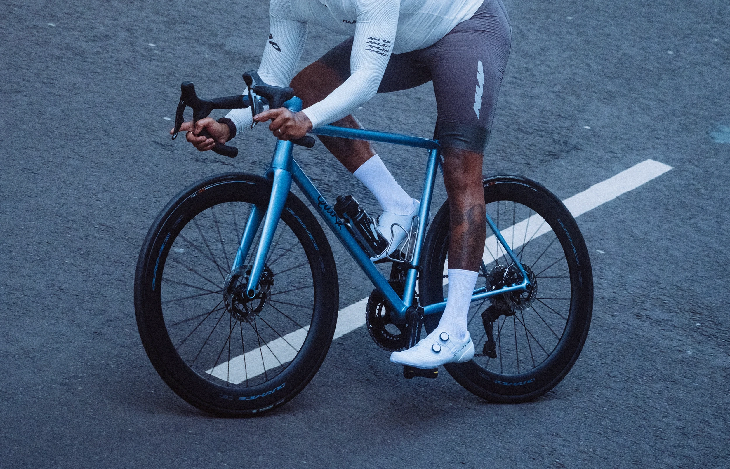 Light blue Quirk Cycles Durmitor road bike in a workshop with dark wheels