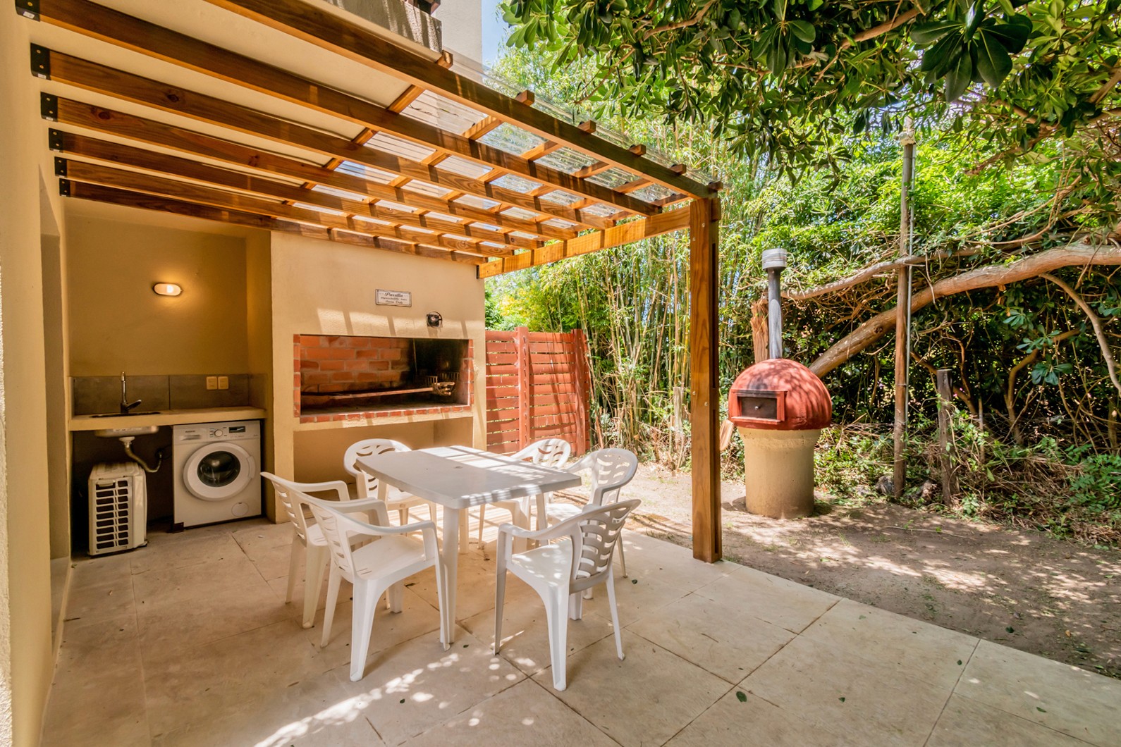 Patio trasero de Casa Albatros con parrillero y mesa techada - área exterior ideal para reuniones y asados al aire libre.