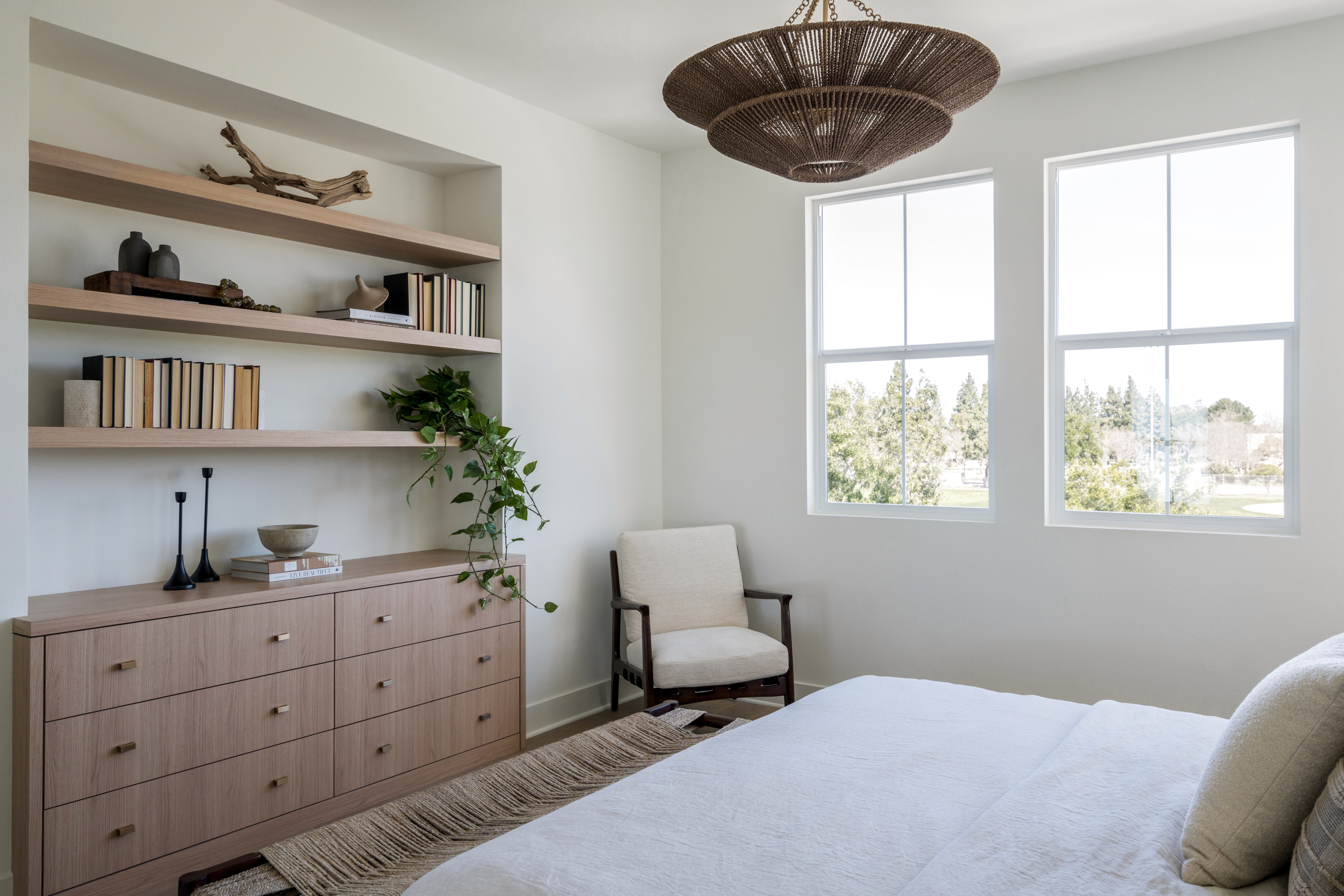 Open wood shelving and built in dresser, shelving styled with antique books, driftwood, greenery, ceramics, and black tapers