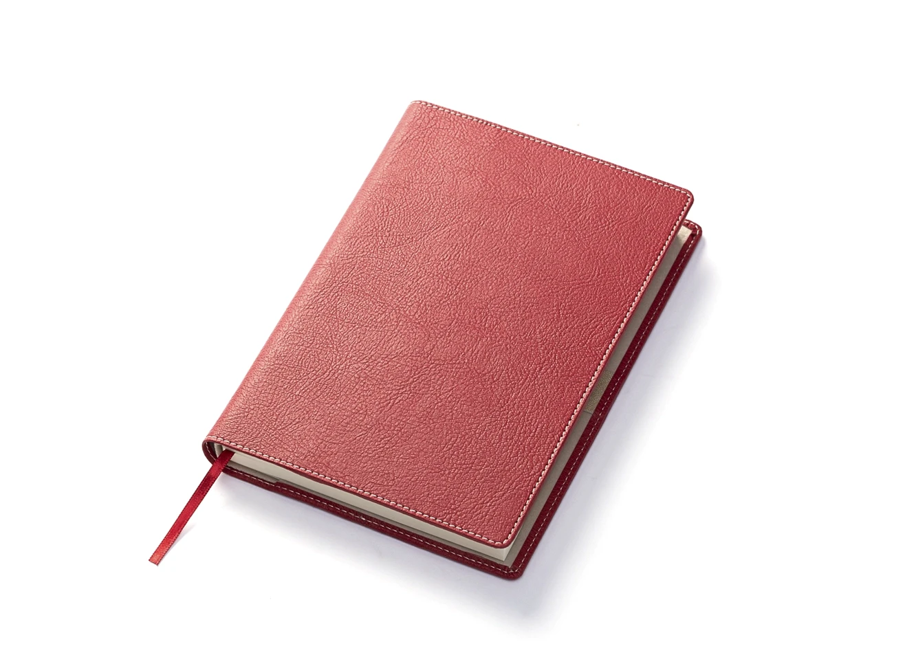 Angled view of closed red notebook with red ribbon bookmark.
