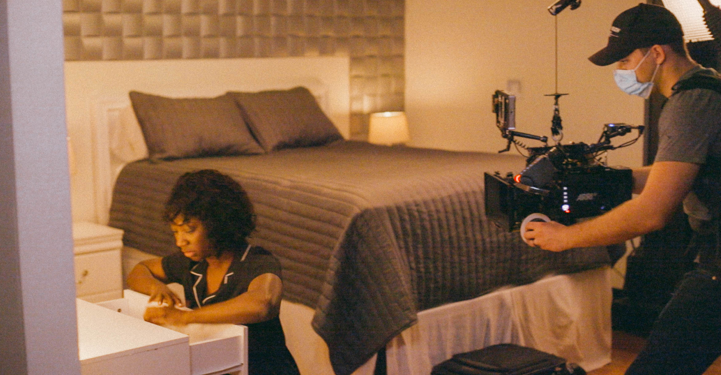 Cooper Ulrich, Director of Photography, films Natasha Ofili as Amara/Sade (a dark-skinned Black woman) at a desk in a bedroom setting with warm lighting.