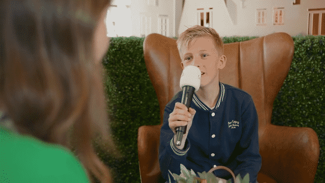 Sfeershot: Kind houdt microfoon met Cedra-logo vast tijdens interview met oudere bewoner in verzorgingstehuis, Dag van de Zorg