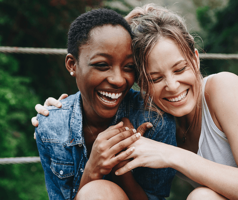 A man in a blue bomber jacket stands against a dark background. The lighting is dramatic, highlighting his focused expression. His pose is confident.