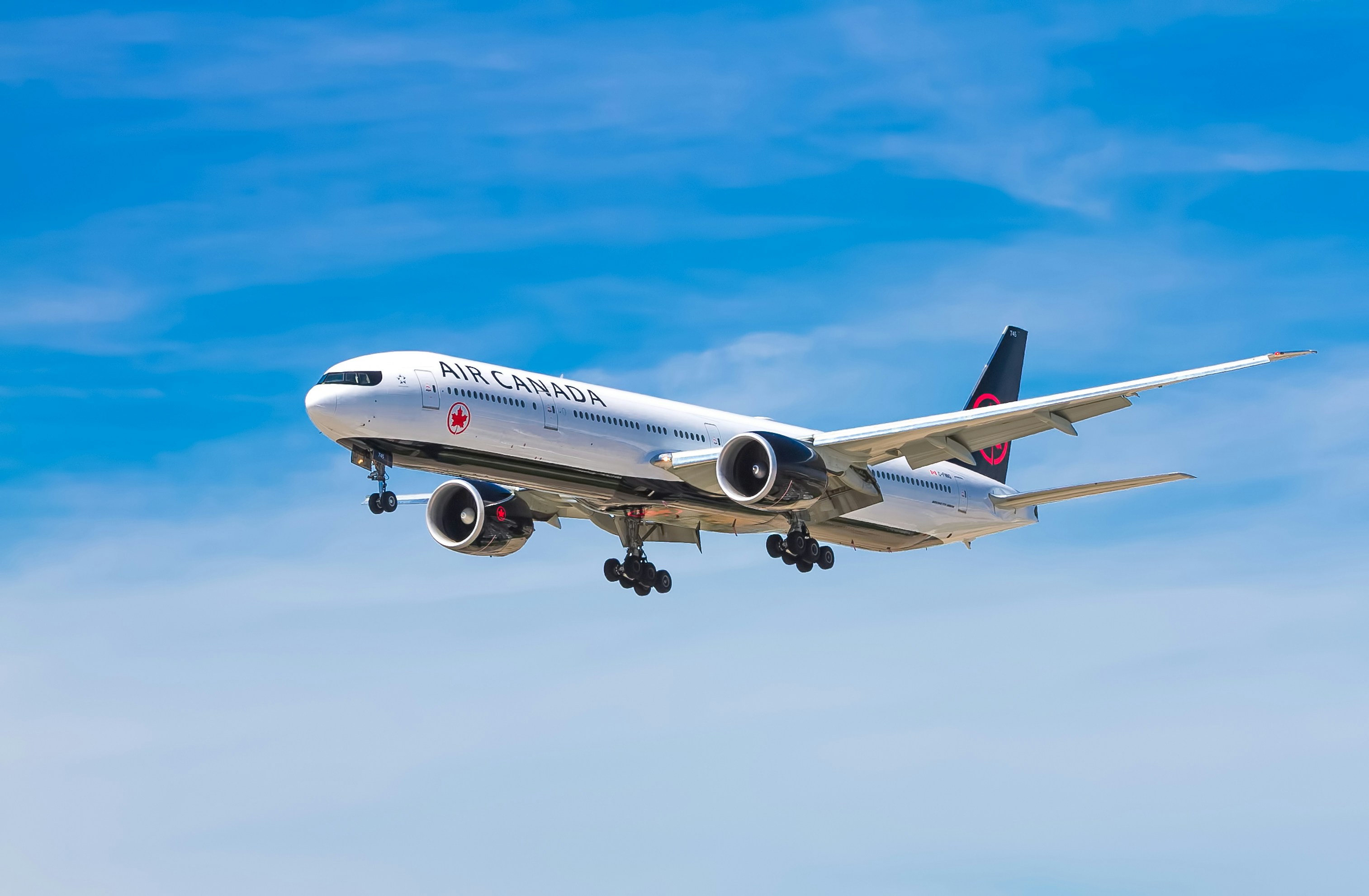 An Air Canada airplane flying in a blue sky. 