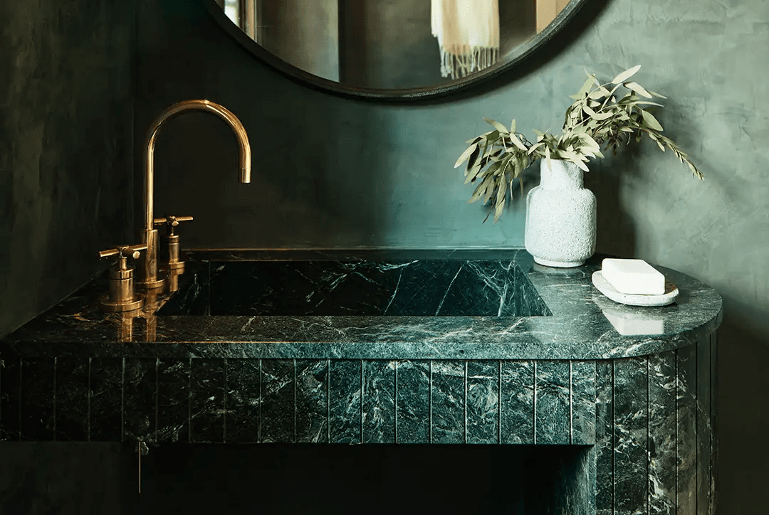 Roman clay behind green marble sink in bathroo