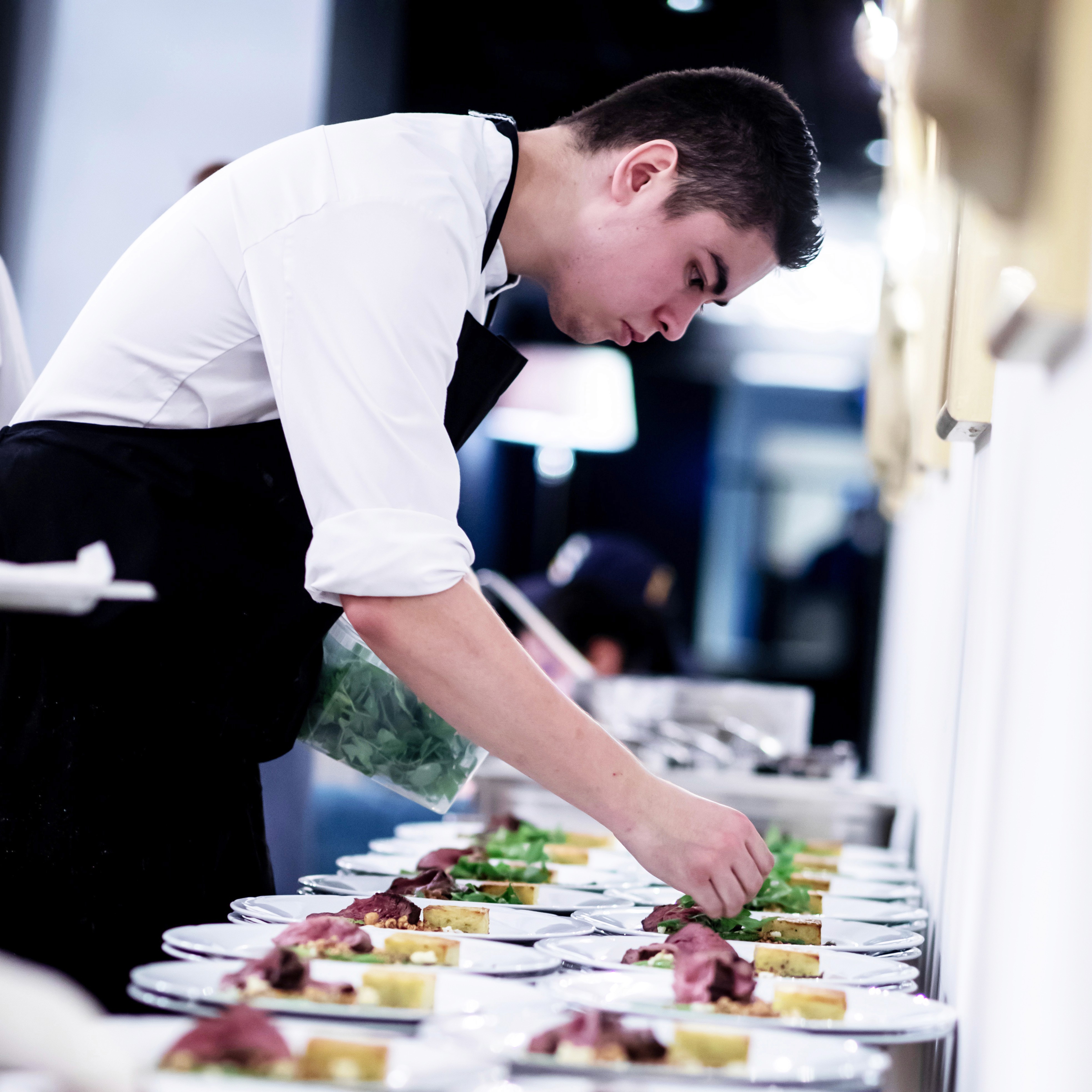 A person in an apron plating a meal