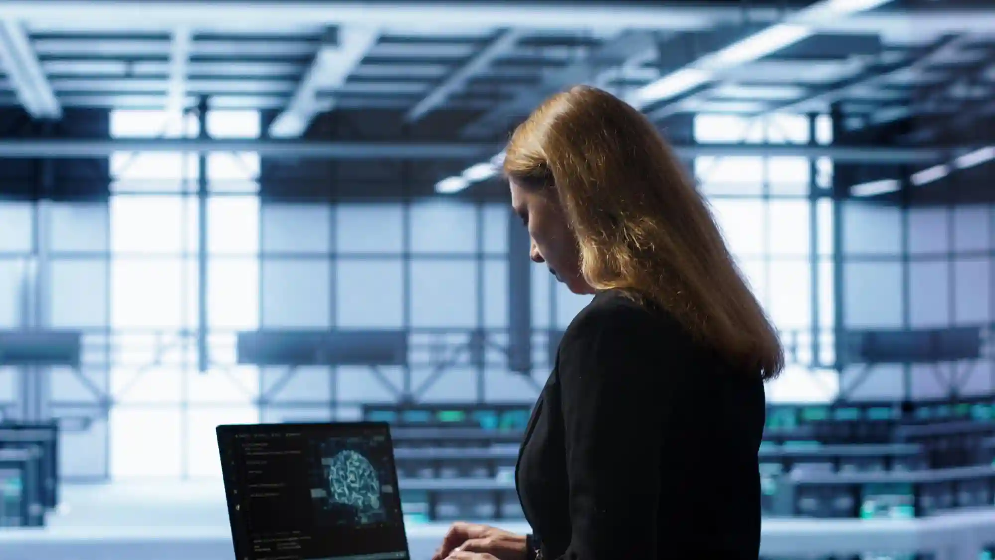 A woman uses a laptop displaying a digital brain in a high-tech data center or command control room.