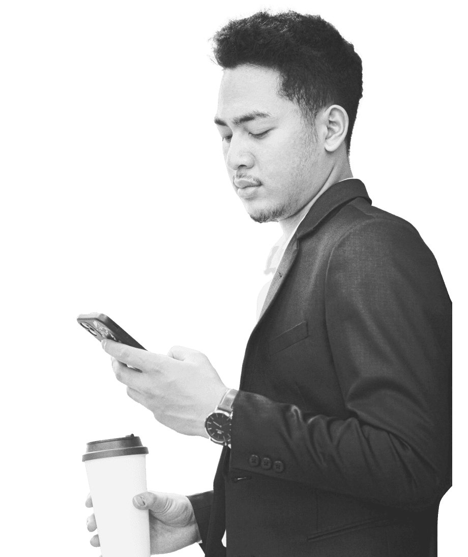 A person in a suit intently checks their smartphone while holding a coffee cup, possibly monitoring indices trading updates.