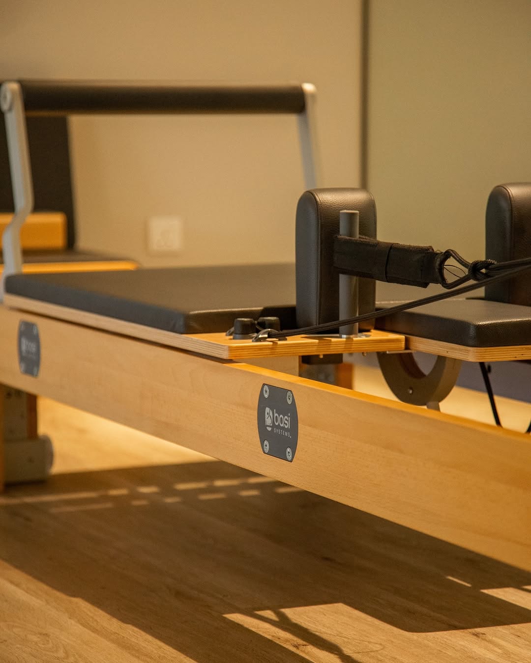 Close-up view of a pilates reformer machine in a modern gym setting.