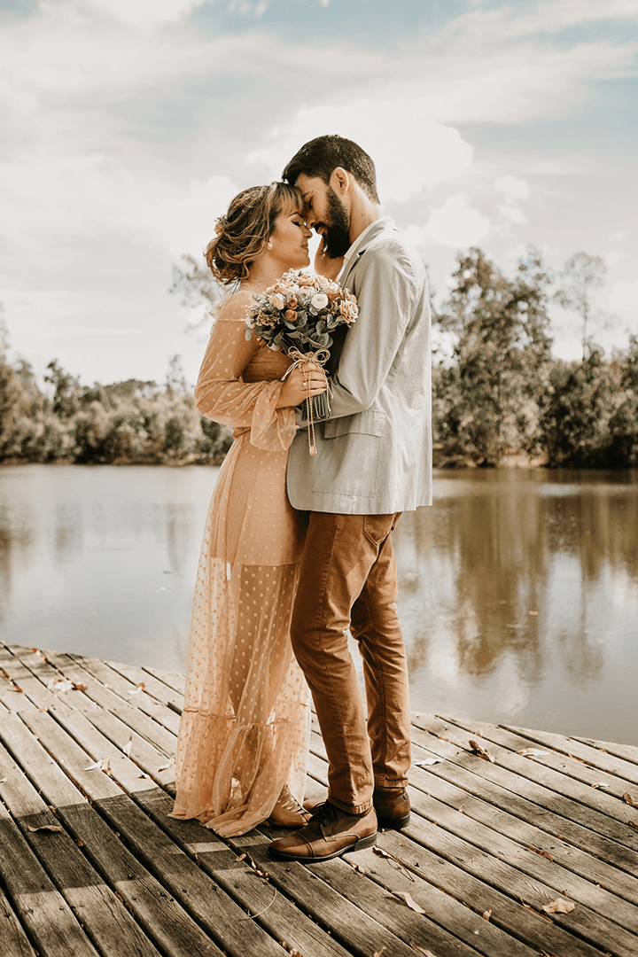 A couple embraces lovingly on a wooden dock.