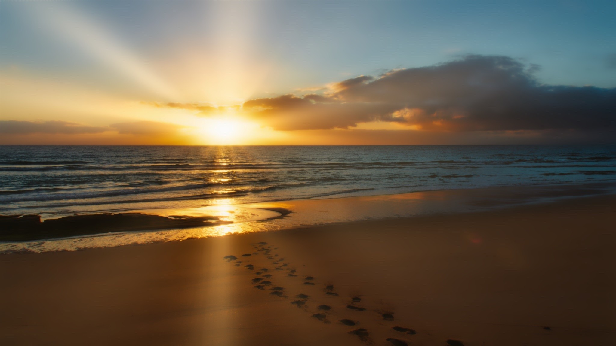 Sonnenaufgang in Fuerte am Meer mit schönen Reflexionen des Lichtes und Fusstapfen im Sand – sanft und wundervoll.