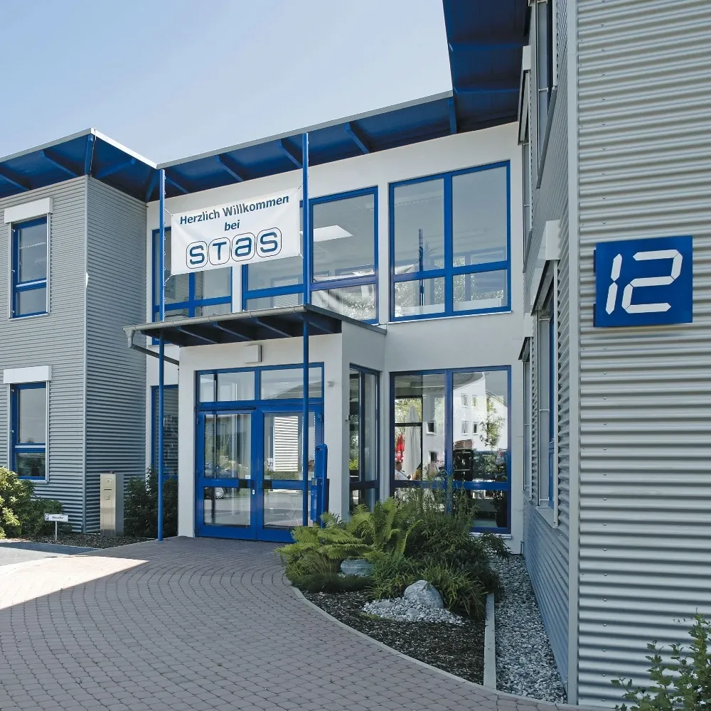 Moderne Firmengebäude mit blauen Fenstern, einem Willkommensbanner und der Hausnummer 12 an der Fassade.