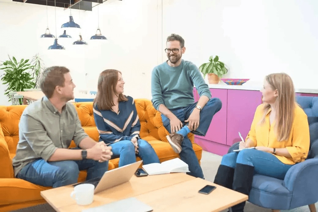 Some people sitting on a couch near drinks.