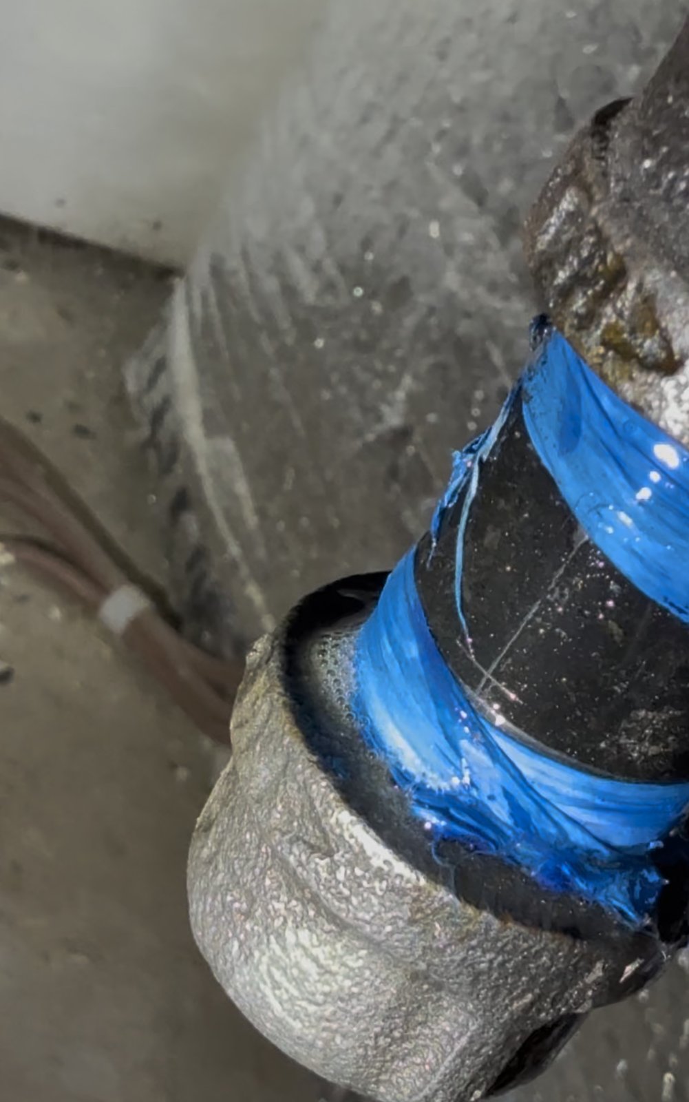 Soap solution applied to a gas fitting during leak testing, with bubbles forming at the joint.